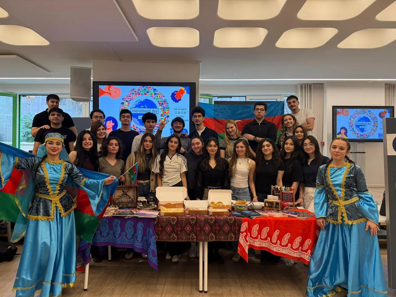 Les membres de l'IRS et deux artistes en costume national derrière le stand de l'Azerbaïdjan à l'International Day