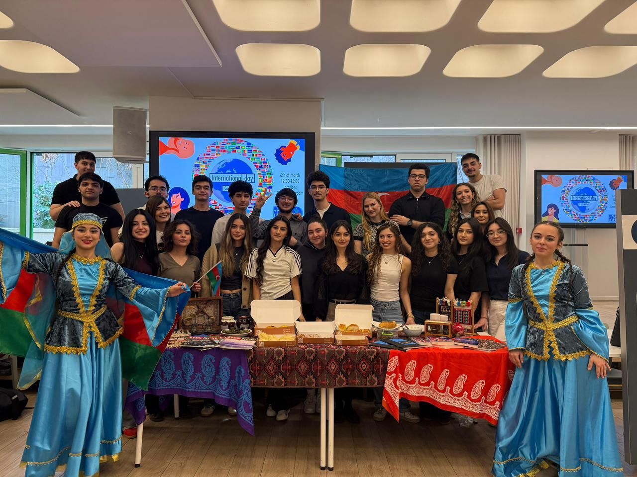 Les membres de l'IRS et deux artistes en costume national derrière le stand de l'Azerbaïdjan à l'International Day