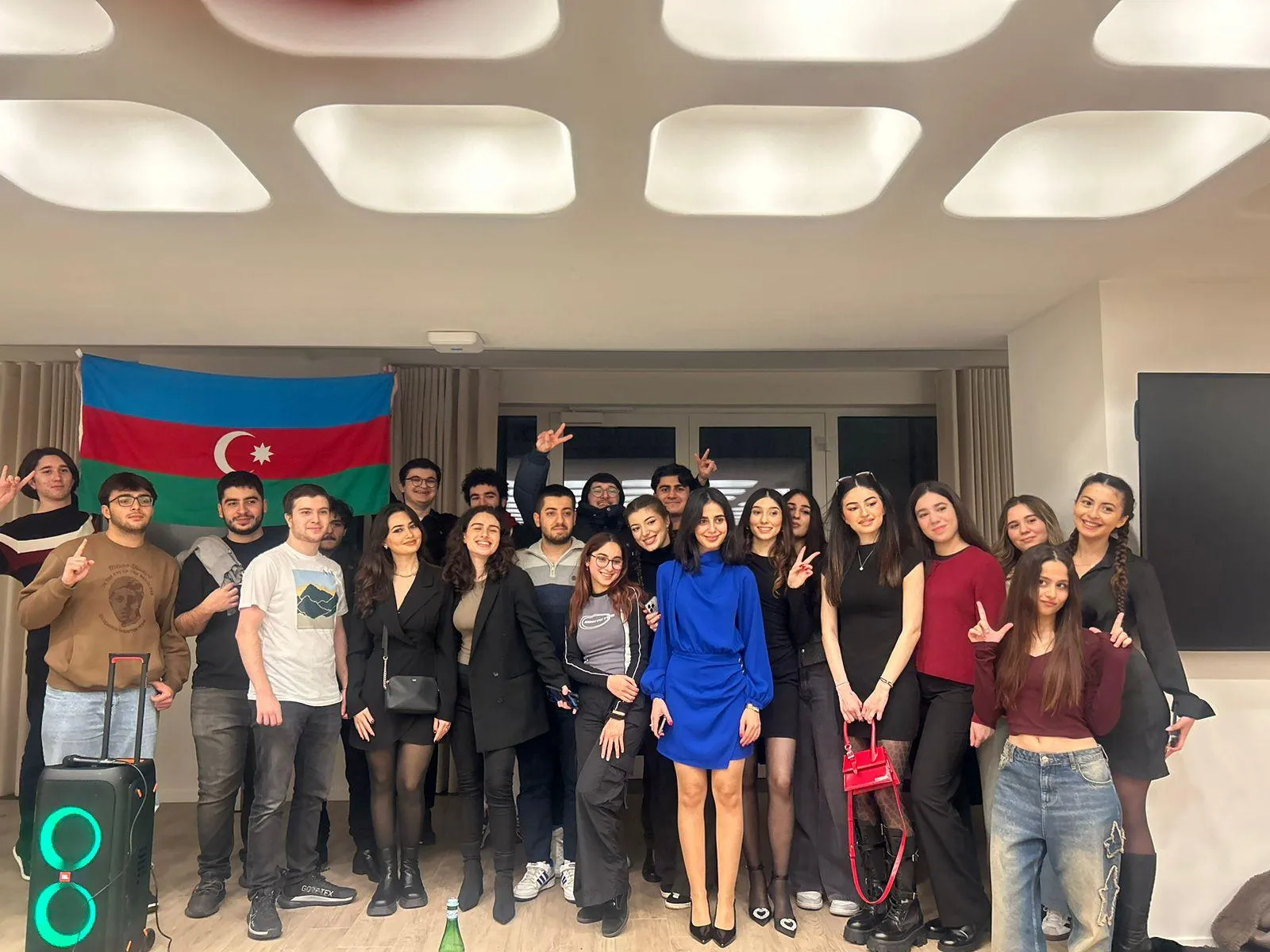 Un grand groupe d'étudiants souriant devant le drapeau azerbaïdjanais lors d'une soirée