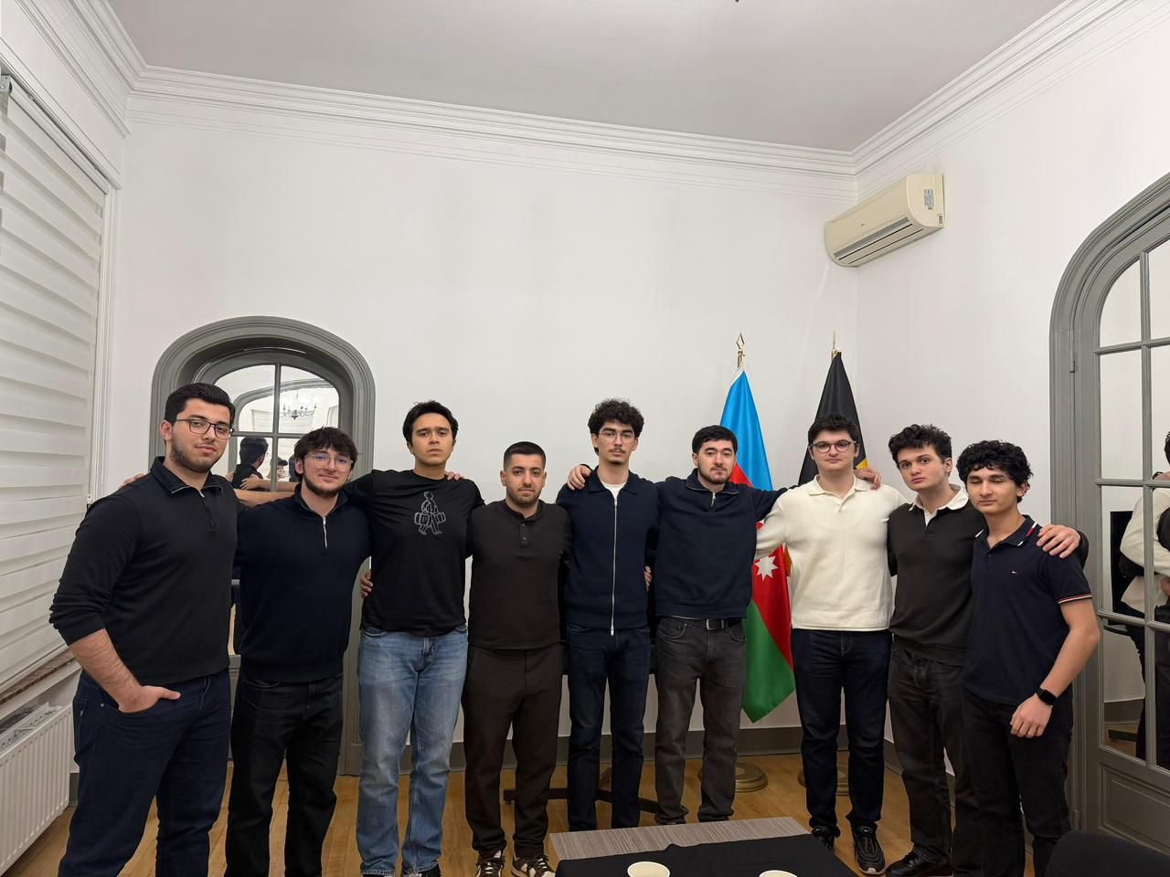 Neuf membres de l'IRS bras dessus, bras dessous devant les drapeaux de l'Azerbaïdjan et de la Belgique